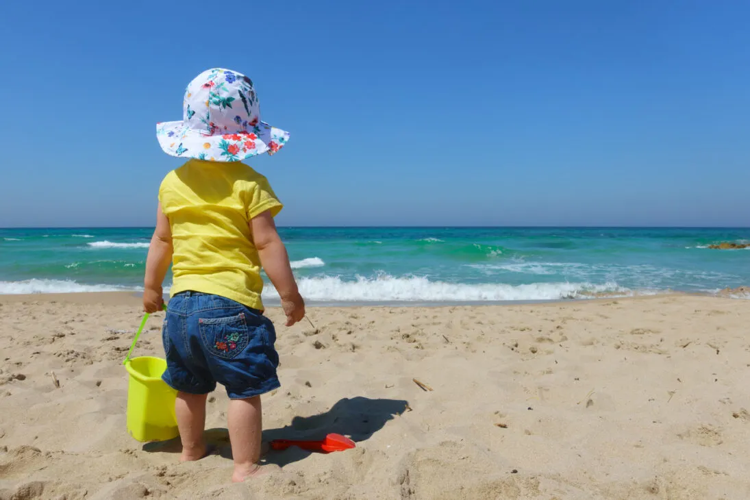 infant-playing-with-the-sand-on-the-beach-PBNZPFH-1095x730