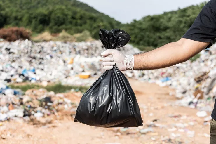 mano-sosteniendo-bolsa-basura-negra-frente-gran-montana-monton-basura-basuras-plasticas-origen-industrial-comunitario-dia-mundial-medio-ambiente_208349-1388